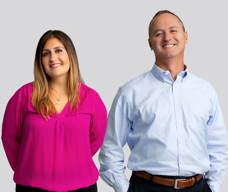 two employees wearing office attire and smiling